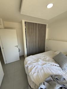 a bedroom with a white bed and a door at Edificio EIFER V a 200 metros de la Av San Bernardo y a 200 metros del Mar con Aire Acondicionado Cochera Cubierta Balcón a la calle Parrilla y Lavadero in San Bernardo