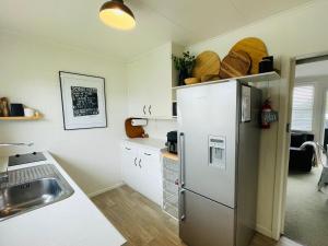 une cuisine avec un réfrigérateur en acier inoxydable et un évier dans l'établissement Beach Apartments at Flaxmill Bay Motel, à Cooks Beach