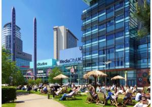 eine Gruppe von Menschen, die in Gartenstühlen vor einem Gebäude sitzen in der Unterkunft Luxury 3 Bedroom Penthouse Apartment in Manchester
