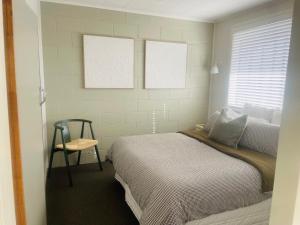 une chambre avec un lit et une chaise dedans dans l'établissement Beach Apartments at Flaxmill Bay Motel, à Cooks Beach