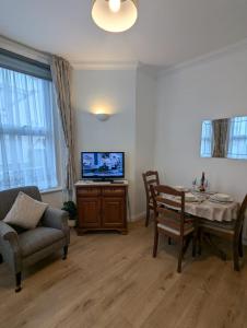 ein Wohnzimmer mit Tisch und Fernseher in der Unterkunft SWANAGE WELL PRESENTED 2 BEDROOM APARTMENT CLOSE to BEACH in Swanage