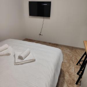 a white bed with two towels and a tv on the wall at Rea Apartments in Belgrade