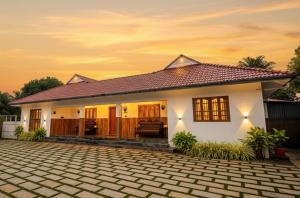 a white house with a brick driveway in front of it at 2 Bedroom Private Villa near the beach in Alleppey