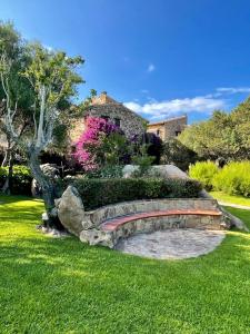 a stone bench in the grass in front of a house at Amazing view apartment in Porto Rotondo
