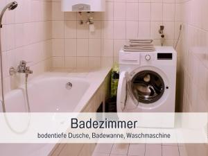 a bathroom with a washing machine and a bath tub at Waldrefugium nahe Gmunden - Ferienapartment für Familie und Hund in Pinsdorf