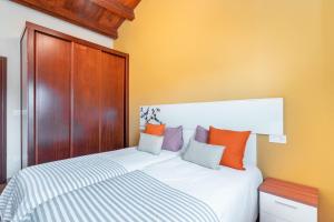 La Campachalet en san justo的卧室配有白色床和橙色及紫色枕头