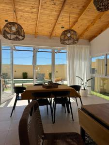 Un comedor con mesa y sillas y ventanas. en Esmeralda, en San Benito