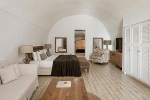 a white bedroom with a bed and a couch at Aqua Luxury Suites by NOMÉE Hospitality Group in Imerovigli
