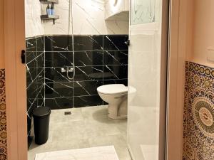 a bathroom with a toilet and a black tiled wall at Maison traditionnelle totalement privée au médina in Chefchaouene +33 photos