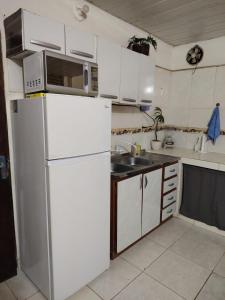 Una cocina con un refrigerador blanco y un fregadero. en Hospedaje SKYHOME II, en Nu Guazu