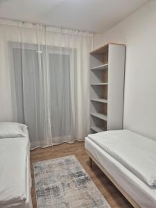Dormitorio blanco con cama y estante de libros en Rezidencia pri Kaštieli 5, en Sokoľany 1 foto más