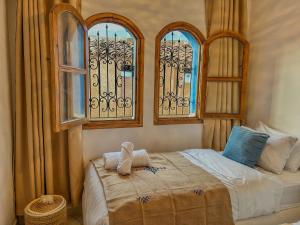 a bedroom with a bed with two windows at Maison traditionnelle totalement privée au médina in Chefchaouene