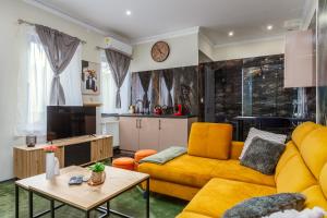 a living room with a yellow couch and a tv at Old Town Treasure Apartments in Debrecen