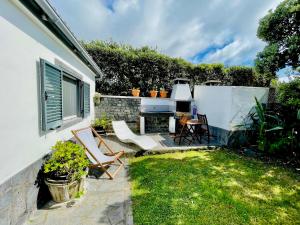 une cour arrière avec une table, des chaises et un barbecue dans l'établissement Sea Roots "Garden Zone ", à Mosteiros