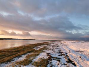 a snowy beach with a cloudy sky and water at 4 person holiday home in Læsø-By Traum in Læsø +20 photos