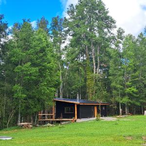 a cabin in the middle of a field with trees at Refugio en Los Arrayanes in Valdivia