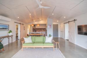 a living room with a green couch and a kitchen at Purangi Views in Cooks Beach