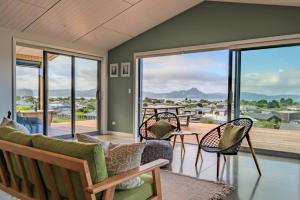 a living room with chairs and a balcony with a view at Purangi Views in Cooks Beach
