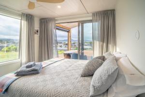 a bedroom with a large bed with a large window at Purangi Views in Cooks Beach