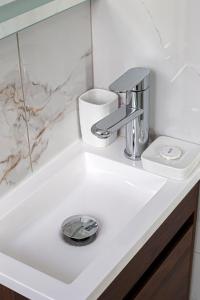 Un lavabo de baño blanco con grifo cromado. en Birzebbuga Sunset, en Birżebbuġa