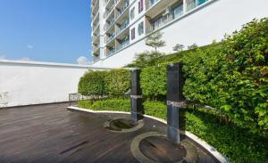 Una terraza con un edificio y un seto verde. en Cozy Stay Pool Atlantis Residence, en Melaka