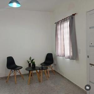 drei Stühle und ein Tisch in einem Raum mit einem Fenster in der Unterkunft Duplex La Luna in Mar del Tuyú