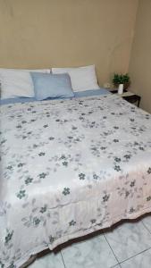 ein Bett mit einer weißen Decke mit Blumen darauf in der Unterkunft Habitación en Residencia Familiar in Asunción
