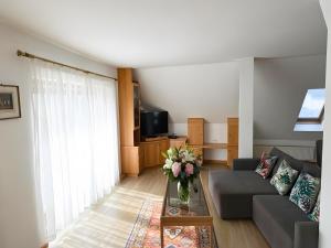 ein Wohnzimmer mit einem Sofa und einer Vase aus Blumen in der Unterkunft Salzkammergut Homes Gmunden - See- und Stadtblick, zentrale Lage, Balkon - ideal für Familien in Gmunden