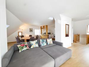 ein Wohnzimmer mit einer grauen Couch mit Kissen in der Unterkunft Salzkammergut Homes Gmunden - See- und Stadtblick, zentrale Lage, Balkon - ideal für Familien in Gmunden
