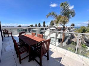 eine Terrasse mit Tisch und Stühlen auf einem Balkon in der Unterkunft 6 on Adams in Mount Maunganui