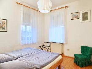 ein Schlafzimmer mit einem Bett und einem grünen Stuhl in der Unterkunft Salzkammergut Homes Gmunden - See- und Stadtblick, zentrale Lage, Balkon - ideal für Familien in Gmunden