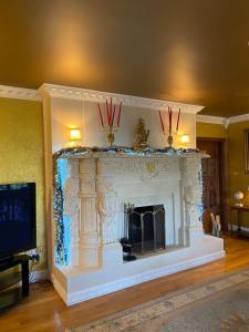 Una sala de estar con una chimenea blanca con adornos navideños. en Winterwood, en Listowel