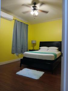 a bedroom with a bed and a ceiling fan at ToniqueluxeGuesthouse in Montego Bay