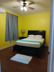 a bedroom with a bed and a ceiling fan at ToniqueluxeGuesthouse in Montego Bay