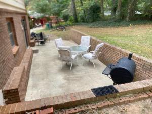 a patio with a grill and chairs and a table at Peaceful 4BR Haven in Stn Mtn GA in Stone Mountain