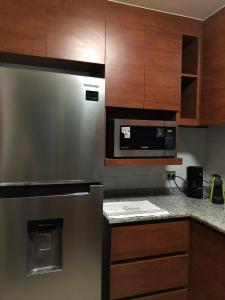 El CerrilloDepto en Viña del Mar Mariposa 2 suites的厨房配有不锈钢冰箱和木制橱柜