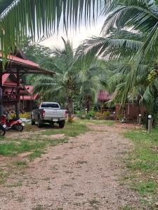 een vrachtwagen geparkeerd voor een huis met palmbomen bij Fadel Bungalow ฟาดิลบังกะโล in Ban Lo Pa Ret +1 foto