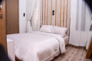 un letto con lenzuola e cuscini bianchi in una stanza di Grand Luxury Apartment a Lekki