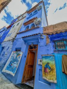 a blue house with a painting on the door at Chambre Lumineuse avec Vue Ruelle Bleue et Terrasse in Chefchaouene