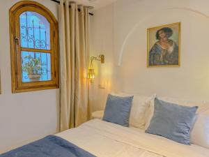 a bedroom with a bed with blue pillows and a window at Chambre Lumineuse avec Vue Ruelle Bleue et Terrasse in Chefchaouene