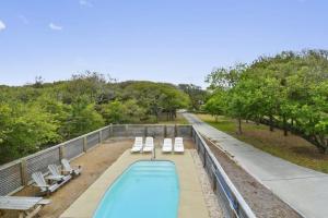 une piscine avec des chaises longues blanches et une piscine d'orangage dans l'établissement 3040 - SeaVue, à Southern Shores