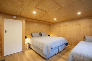 two beds in a room with wooden walls at Mataura River Hideaway in Ardlussa +13 photos
