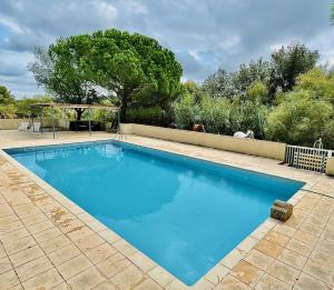 a swimming pool with blue water in a yard at La Camargue Appartment mit Pool in Aigues-Mortes