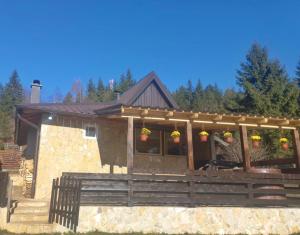 ein Haus mit einer Veranda mit Blumen darauf in der Unterkunft Planinska kuca ANDJELA 2 in Mitrovac + 9 Fotos