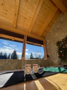 Zwei Tassen stehen auf einem Tisch in einem Zimmer mit Fenster in der Unterkunft Planinska kuca ANDJELA 2 in Mitrovac
