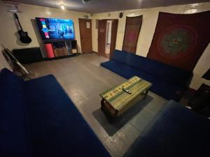 une pièce avec des canapés bleus, une table et une télévision dans l'établissement Intihuatana Hostel, à Pisac
