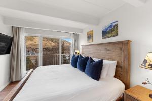 Un dormitorio con una cama con almohadas azules y una ventana. en The Lodge at Lake Dillon 111, en Dillon