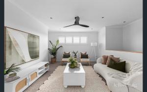 ein Wohnzimmer mit einem weißen Sofa und einem Fernseher in der Unterkunft Pool House Barwon Heads 4 bedroom 2 bathroom Pool Great Yard Family friendly in Barwon Heads