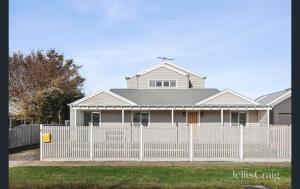 einen weißen Zaun vor einem weißen Haus in der Unterkunft Pool House Barwon Heads 4 bedroom 2 bathroom Pool Great Yard Family friendly in Barwon Heads