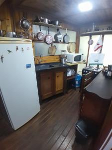 Chalé Bambu في كونها: مطبخ وثلاجة بيضاء وارضية خشبية